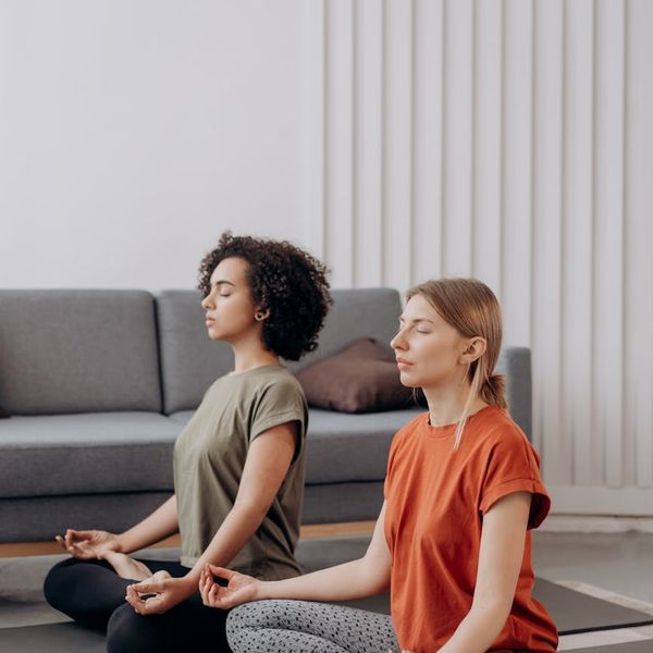 Person meditating peacefully in a room with soft lighting.